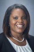 Head shot of Candice Baldwin smiling wearing a blouse with a white pearl necklace and suit jacket.